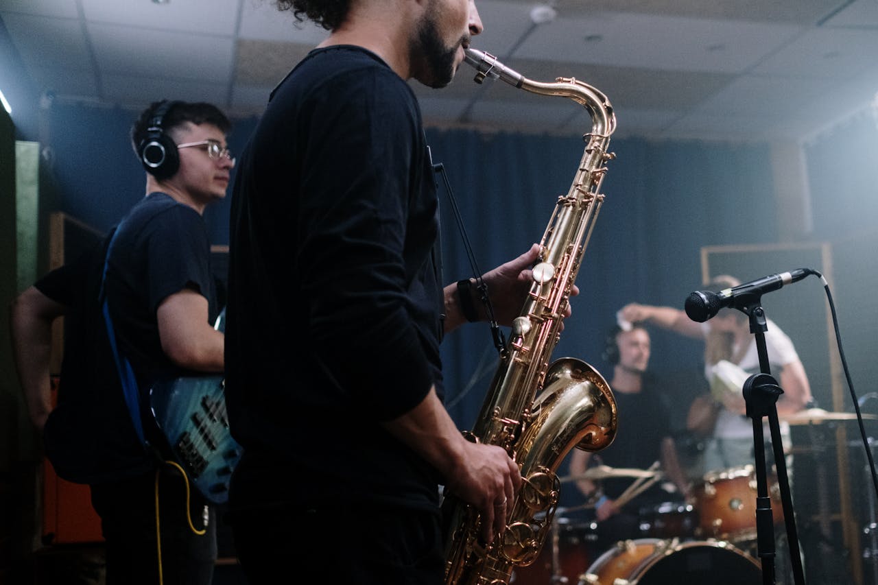 Musicians playing instruments in a recording studio, focusing on saxophonist.